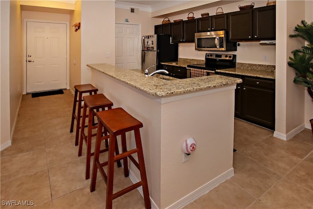 kitchen with light stone countertops, sink, stainless steel appliances, a kitchen breakfast bar, and ornamental molding