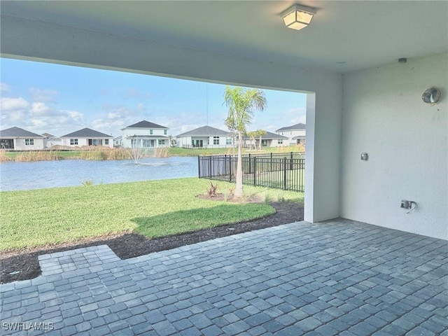 view of patio / terrace featuring a water view, fence, and a residential view