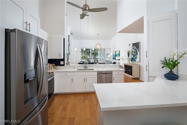 kitchen with kitchen peninsula, stainless steel appliances, white cabinetry, and light hardwood / wood-style floors