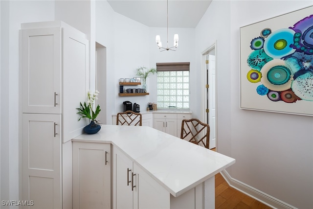 kitchen with kitchen peninsula, white cabinetry, hardwood / wood-style floors, and decorative light fixtures