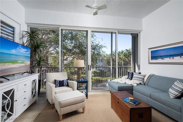 living room with ceiling fan, light tile patterned flooring, and a textured ceiling