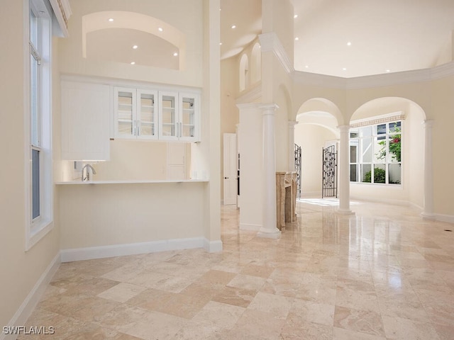 spare room featuring decorative columns and a high ceiling