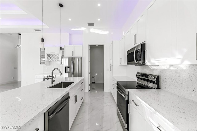 kitchen with light stone countertops, appliances with stainless steel finishes, sink, white cabinetry, and hanging light fixtures