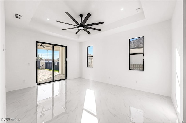 empty room featuring ceiling fan and a raised ceiling