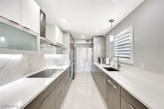 kitchen featuring wall chimney exhaust hood, stainless steel appliances, sink, pendant lighting, and white cabinets