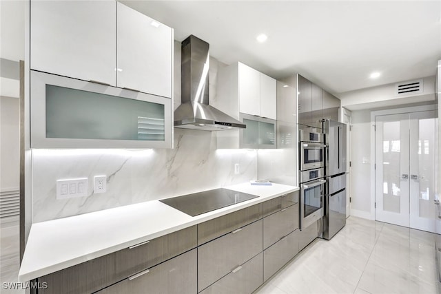 kitchen with black electric stovetop, wall chimney exhaust hood, tasteful backsplash, white cabinetry, and stainless steel double oven