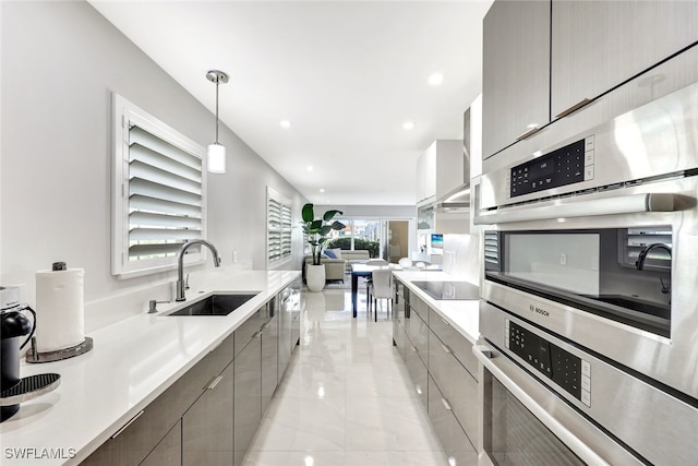 kitchen with wall chimney range hood, pendant lighting, a healthy amount of sunlight, and sink