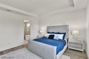 bedroom with hardwood / wood-style floors and ensuite bathroom