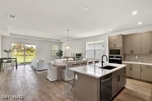 kitchen featuring a center island with sink, wood-type flooring, hanging light fixtures, and appliances with stainless steel finishes