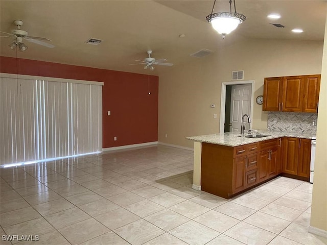 kitchen featuring kitchen peninsula, light stone countertops, sink, hanging light fixtures, and lofted ceiling