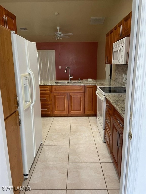 kitchen featuring sink, light stone counters, kitchen peninsula, white appliances, and light tile patterned flooring