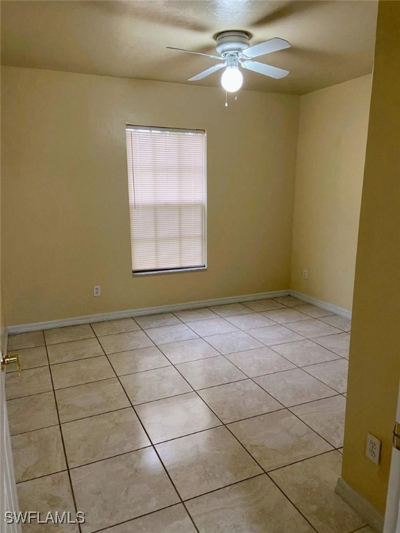 tiled spare room with ceiling fan