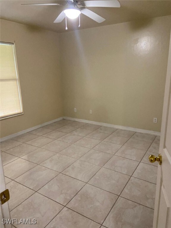 tiled spare room with ceiling fan