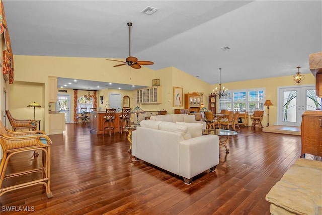 living room with ceiling fan with notable chandelier, dark wood-type flooring, high vaulted ceiling, and french doors