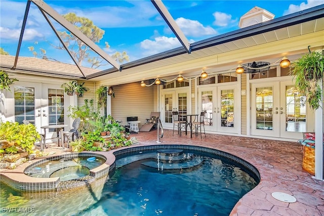 view of pool with glass enclosure, a patio area, an in ground hot tub, and french doors