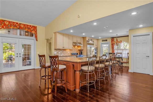 kitchen with hanging light fixtures, dark hardwood / wood-style floors, a wealth of natural light, and a center island with sink