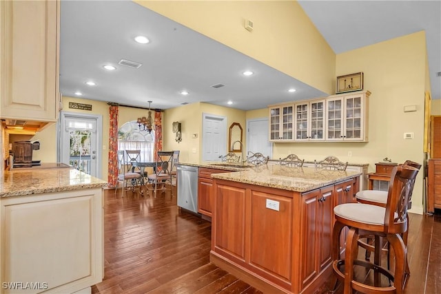 kitchen featuring dishwasher, a center island with sink, light stone countertops, dark hardwood / wood-style flooring, and a breakfast bar area