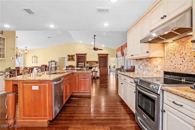 kitchen featuring appliances with stainless steel finishes, a breakfast bar, vaulted ceiling, sink, and dark hardwood / wood-style floors