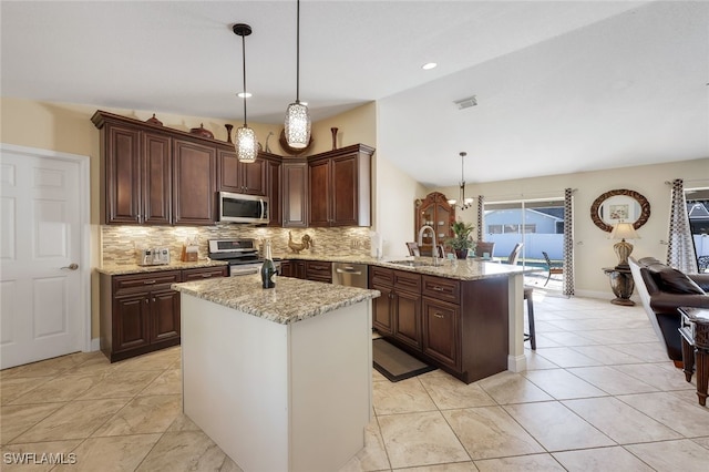 kitchen with kitchen peninsula, light stone countertops, stainless steel appliances, sink, and pendant lighting