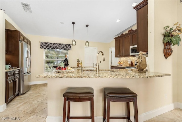 kitchen featuring sink, tasteful backsplash, light stone counters, kitchen peninsula, and stainless steel appliances