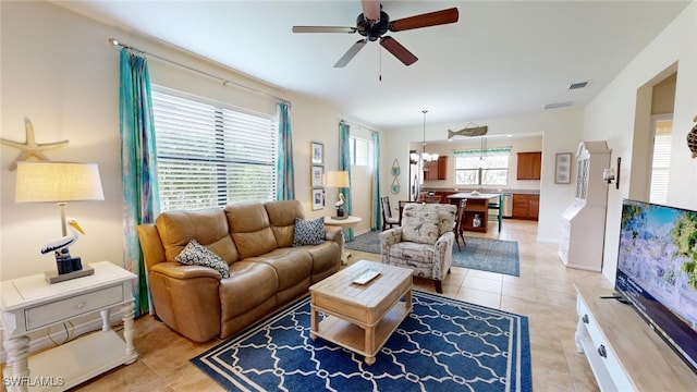 living room featuring light tile patterned flooring and ceiling fan with notable chandelier