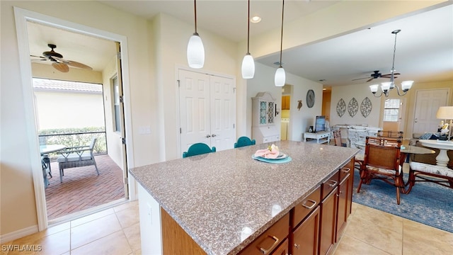 kitchen featuring ceiling fan, hanging light fixtures, a center island, and a healthy amount of sunlight