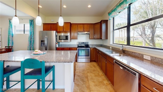 kitchen featuring light stone countertops, a breakfast bar, stainless steel appliances, sink, and a kitchen island