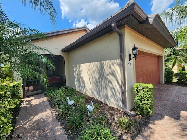 view of home's exterior with decorative driveway, stucco siding, and an attached garage
