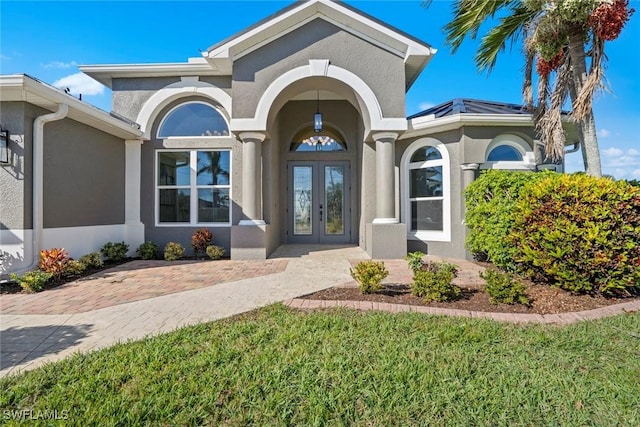 view of exterior entry featuring french doors and a yard