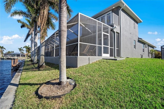 view of side of home featuring a lanai, a lawn, and a water view