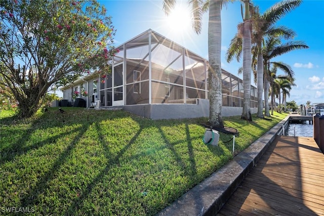 back of property featuring glass enclosure and a lawn