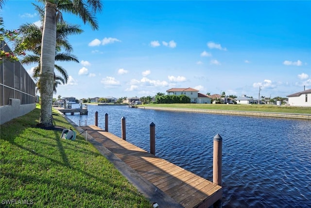 dock with a water view, a residential view, and a lawn
