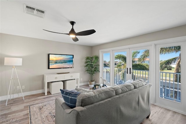 living room featuring ceiling fan, light hardwood / wood-style flooring, and french doors