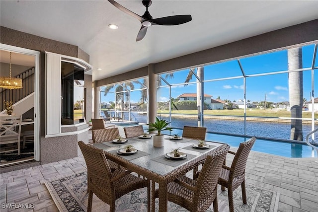 sunroom with a water view and ceiling fan with notable chandelier