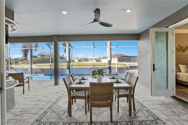 sunroom featuring ceiling fan and a water view