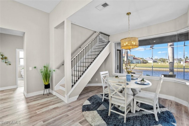 dining area with hardwood / wood-style flooring, a water view, and a chandelier