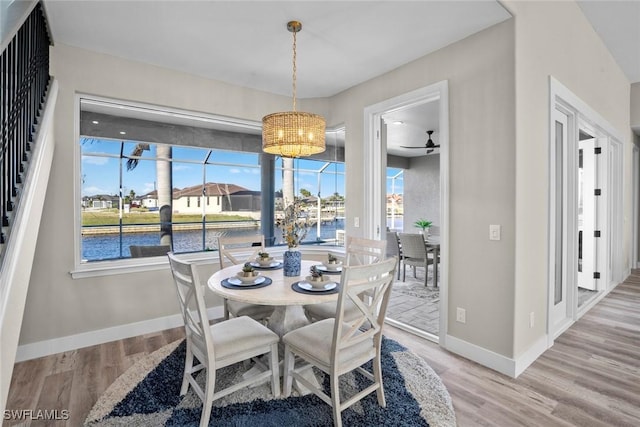 dining space with hardwood / wood-style floors, ceiling fan, and a water view