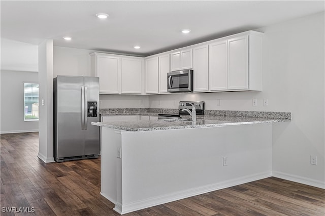 kitchen with kitchen peninsula, white cabinetry, stainless steel appliances, and dark hardwood / wood-style floors