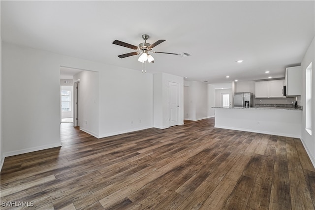 unfurnished living room featuring ceiling fan and dark wood-type flooring