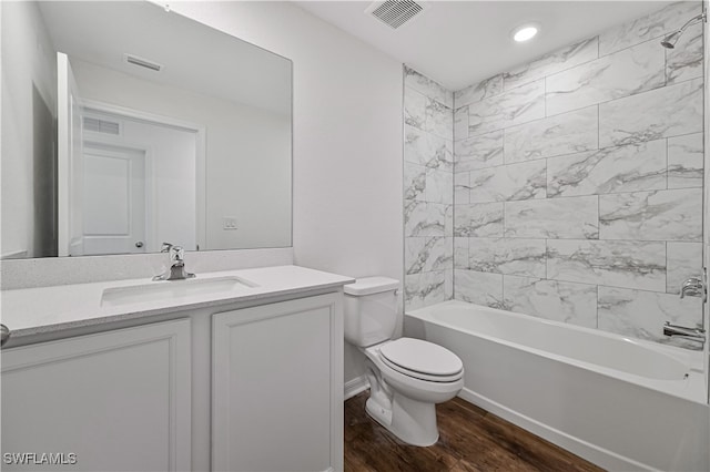 full bathroom featuring hardwood / wood-style floors, vanity, toilet, and tiled shower / bath