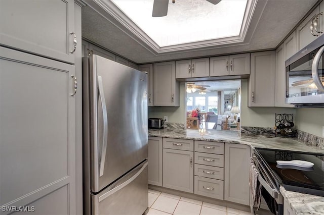 kitchen with light tile patterned floors, a textured ceiling, stainless steel appliances, and gray cabinets