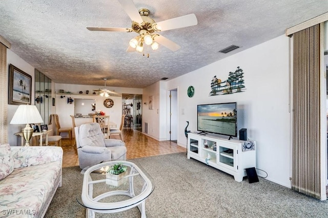 living room featuring carpet flooring, ceiling fan, and a textured ceiling