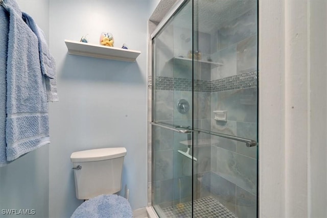 bathroom featuring toilet and a shower with shower door