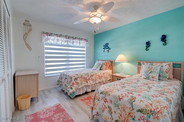 bedroom with ceiling fan, a closet, a textured ceiling, and light wood-type flooring