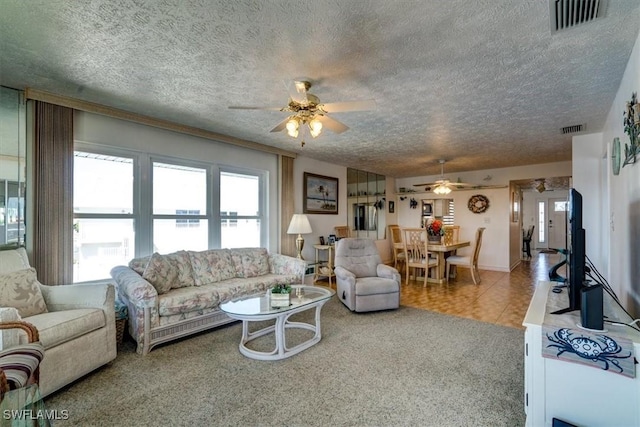 living room featuring carpet, a textured ceiling, and ceiling fan