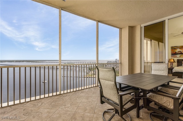 sunroom / solarium with ceiling fan, a water view, and a view of the beach