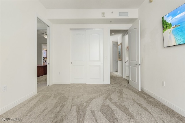 unfurnished bedroom featuring light carpet and a closet