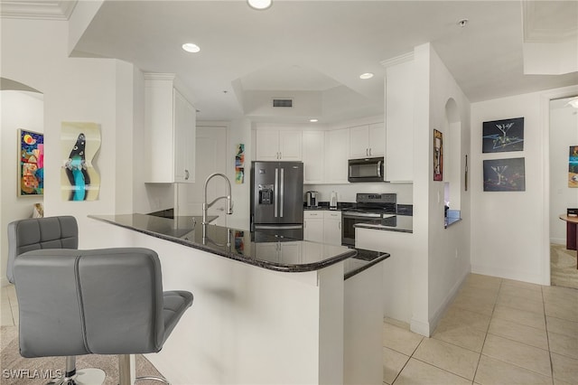 kitchen featuring kitchen peninsula, appliances with stainless steel finishes, a breakfast bar, and white cabinetry