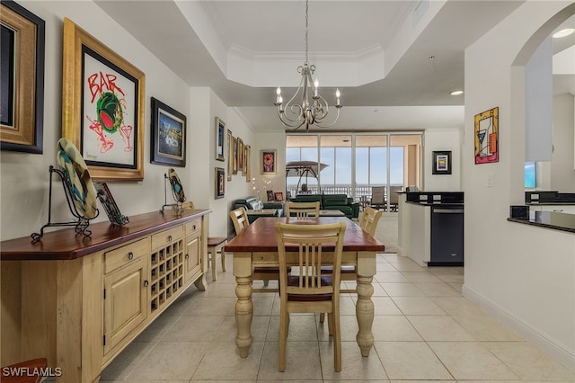 dining space with a chandelier, light tile patterned floors, a tray ceiling, and ornamental molding