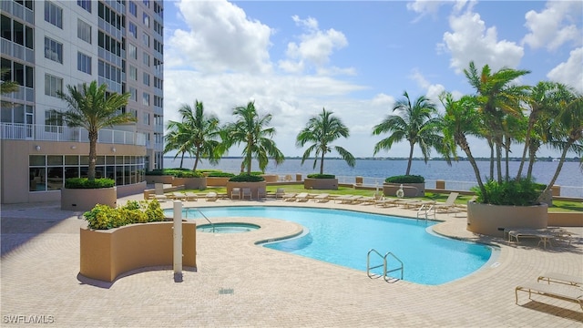 view of pool featuring a community hot tub, a water view, and a patio area